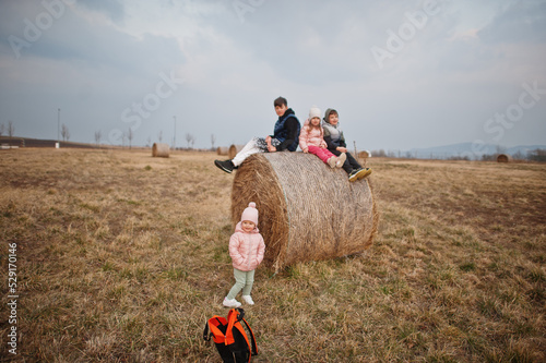 Four kids sitting on haycock at field. photo