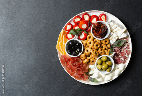 Classic italian antipasti or tapas wine snacks set. Cheese variety, black and green olives, pickles, prosciutto di Parma, tomatoes, salami, tarallini. Flat lay, top view, copy space for text