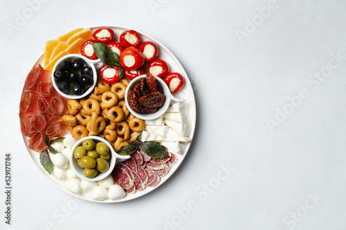 Classic italian antipasti or tapas wine snacks set. Cheese variety, black and green olives, pickles, prosciutto di Parma, tomatoes, salami, tarallini. Flat lay, top view, copy space for text