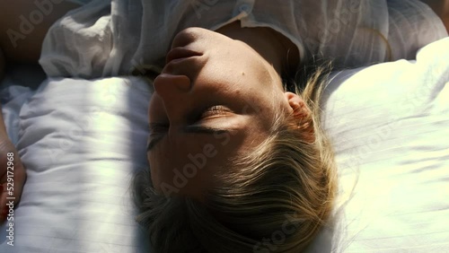 Top view of young sleeping woman writhing her face and twitching from passing dreams. Sleep problems, anxiety, mental disorders, stress. Girl wakes up feeling fear and prostration. Nightmares