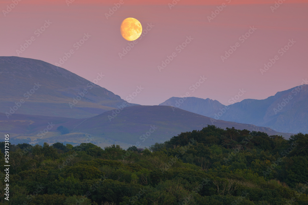 The Moon rising over the Mountains of Snowdonia from Anglesey, North Wales, UK. The Moon rising over the Mountains of Snowdonia from Anglesey, North Wales, UK.