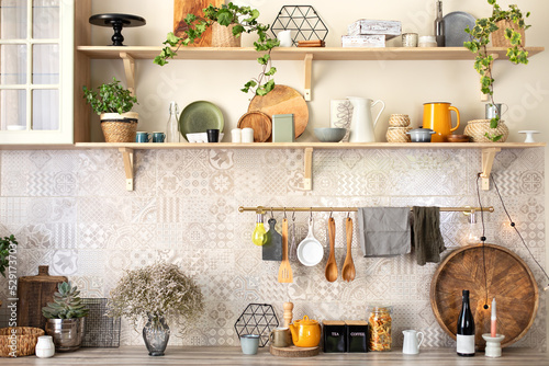 Stylish scandi cuisine interior decor. Ceramic plates, dishes, utensils and cozy decor on wooden shelfs. Kitchen wooden shelves with various ceramic jars and cookware. Open shelves in the kitchen. 