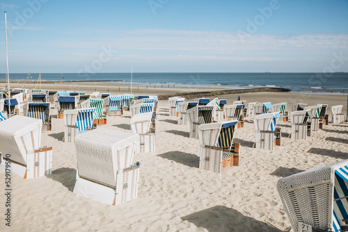 Wide sandy beach on the North Sea with beach chairs. Beach by the sea in Holland, Germany or Denmark. dunes by the sea © Marianna
