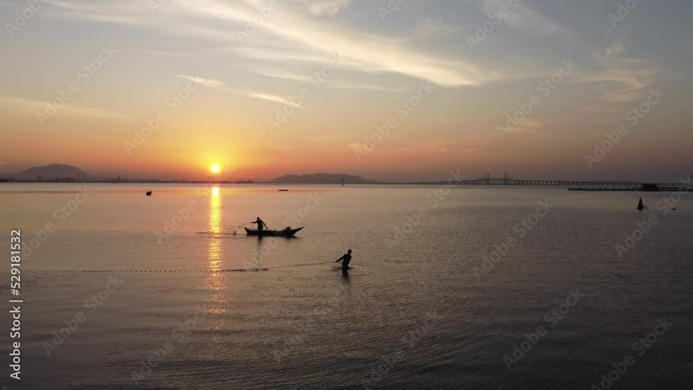 Slowly move toward fisherman catch fish with net in early morning. Background is Penang Bridge Slowly move toward fisherman catch fish with net in early morning. Background is Penang Bridge