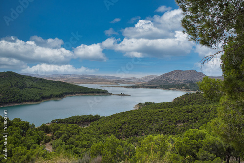 Spectacular panoramic views of the Guadalhorce reservoir, next to the Caminito del Rey in Malaga, Spain. Turquoise blue water and forest with blue sky on a sunny day. © ruthlaguna
