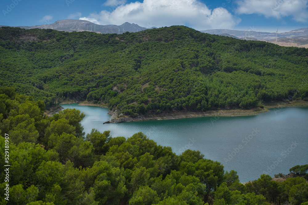 Spectacular panoramic views of the Guadalhorce reservoir, next to the Caminito del Rey in Malaga, Spain. Turquoise blue water and forest with blue sky on a sunny day.