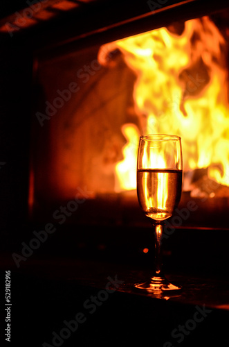 Champagne glasses full of bubbly champagne on the table by the burning flames of a fireplace