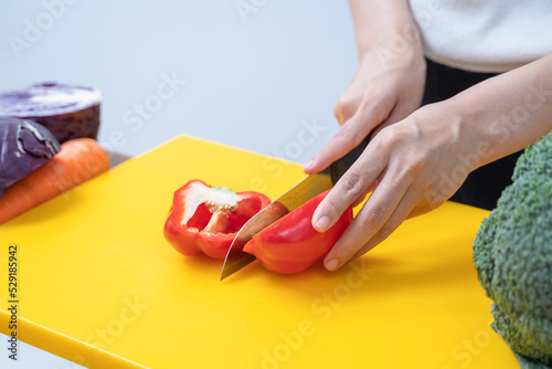 Young woman cutting vegetables in the kitchen. Woman's hands cutting vegetables, behind fresh vegetables. asian woman uses a knife and cooks.