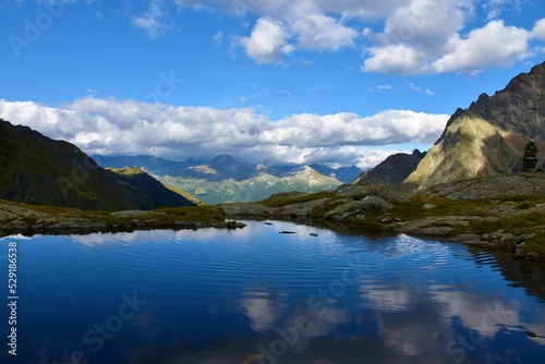 Fototapeta Naklejka Na Ścianę i Meble -  Small lake with a reflection of the sky and the clouds in Gradental valley in Gradental valley in Schober group sub-range of Hohe Tauern in Central Eastern Alps, Carinthia, Austria