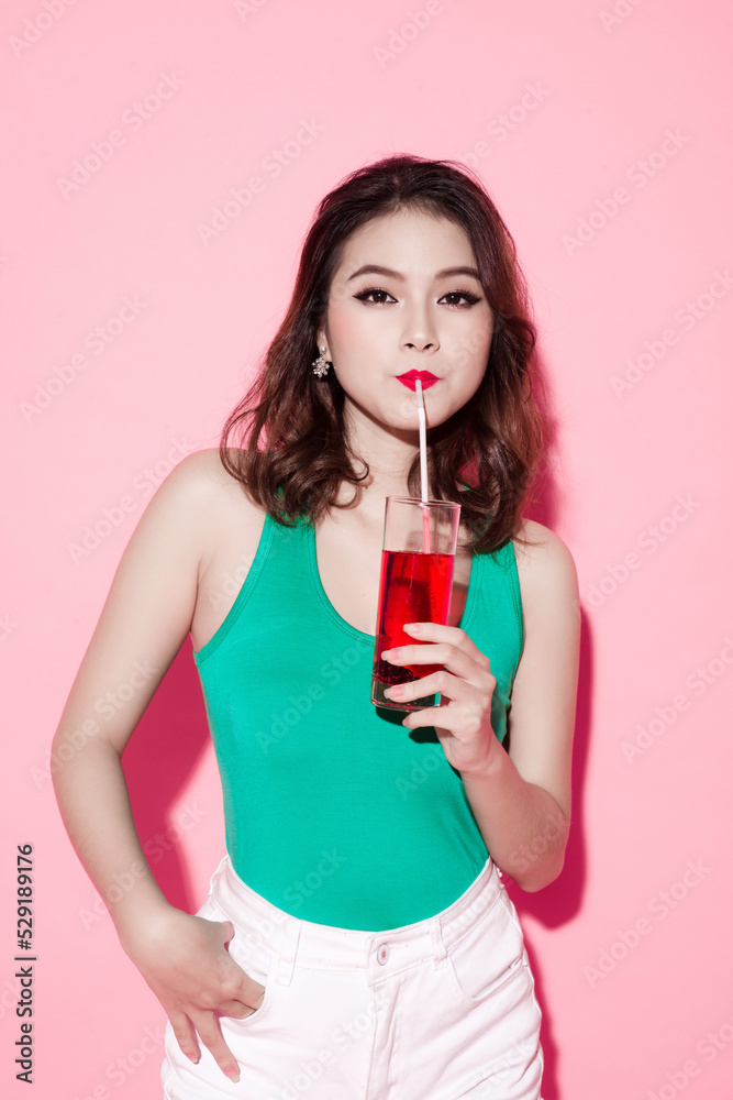 Beautiful girl drinking a cocktail against pink background. Beautiful girl drinking a cocktail against pink background.