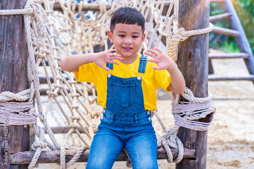 Asian boy put jean enjoy playing rope climbing at the playground. Children's adventure concept photo