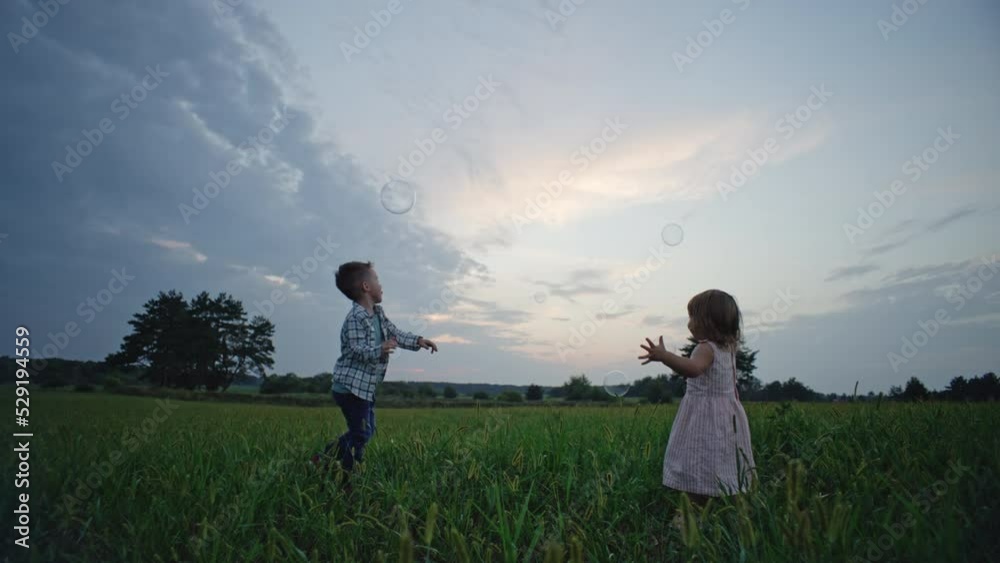 Children play together, breaking soap bubbles in nature. Brother and sister rejoice together running and having fun in the park. High quality 4k footage Children play together, breaking soap bubbles in nature. Brother and sister rejoice together running and having fun in the park. High quality 4k footage