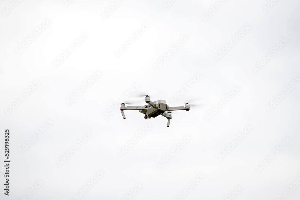 The quadcopter flies in height against the background of a gray sky. The quadcopter flies in height against the background of a gray sky.