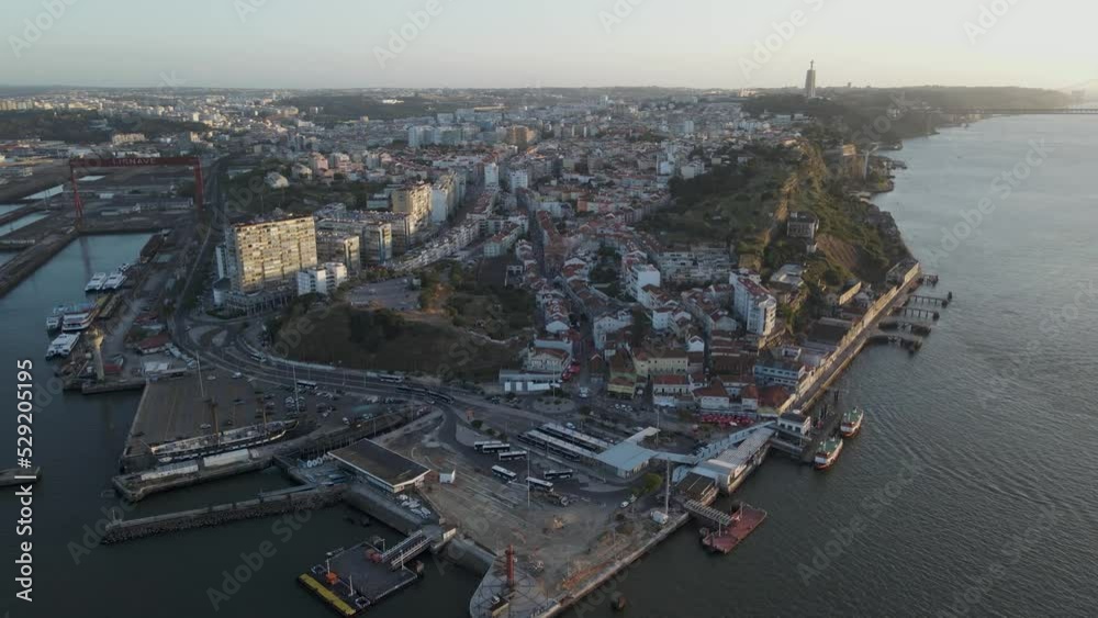 Aerial view of Cacilhas little town along the Tagus river at sunset with April 25th bridge and Cristo Rei statue in background, Almada, Portugal. Aerial view of Cacilhas little town along the Tagus river at sunset with April 25th bridge and Cristo Rei statue in background, Almada, Portugal.