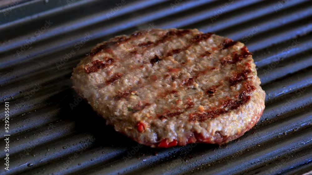 Burger on the grill. The burger is well fryied from one side so the chef with the help spatula turn the burger to the other side and continue grilling. Burger on the grill. The burger is well fryied from one side so the chef with the help spatula turn the burger to the other side and continue grilling.