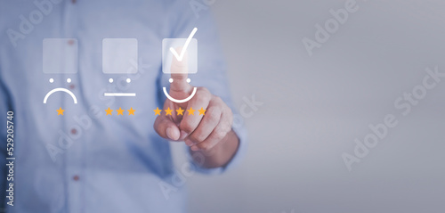 Businessman pressing smiley face button and five star on virtual touch screen for the best evaluation. Customer service evaluation concept.