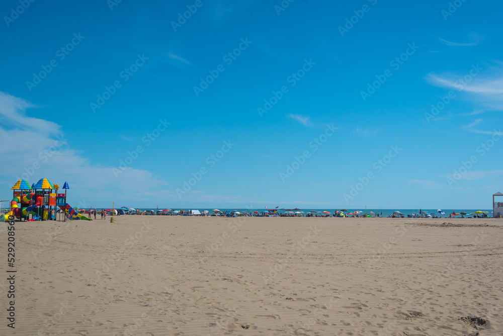 Seashore landscape. Summer holiday destination in Italy. Sandy beach in sunlight.