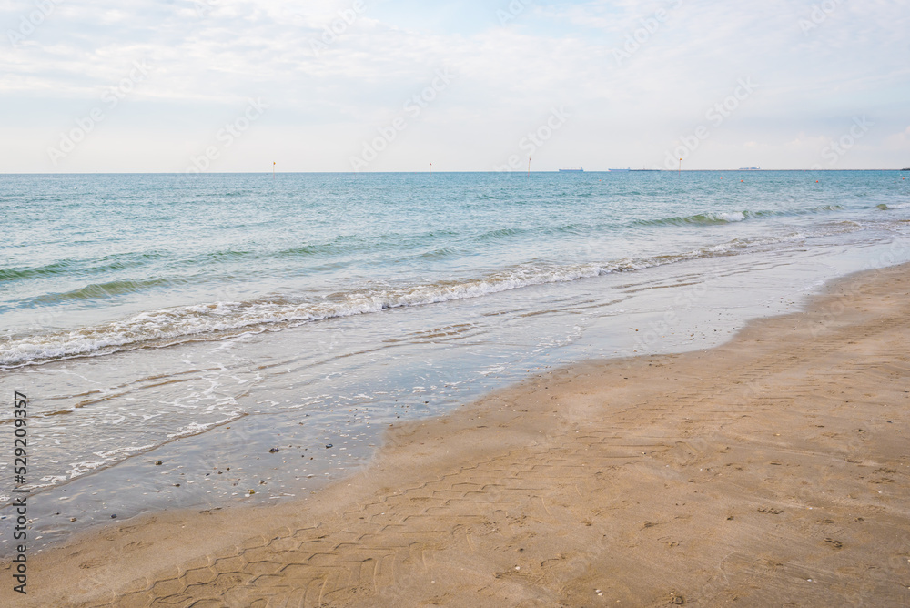 Seashore landscape. Summer holiday destination in Italy. Sandy beach in sunlight.