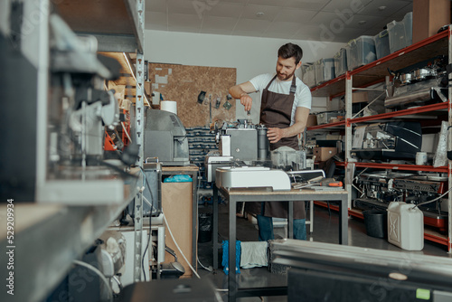 Man worker repairing coffee machine on own workshop