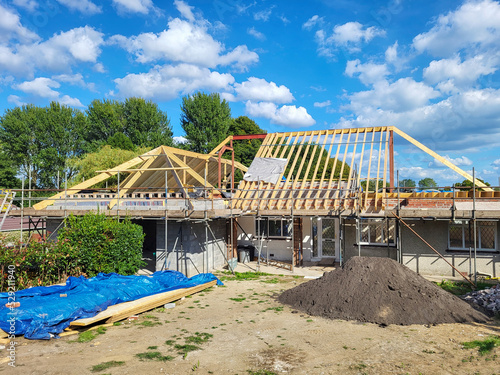 Single story self-build house during construction with scaffolding and exposed roof timbers.