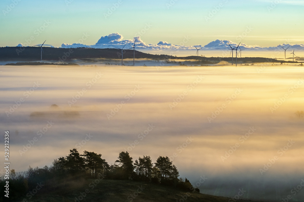 Aerial view at a sunrise with mist and wind turbines
