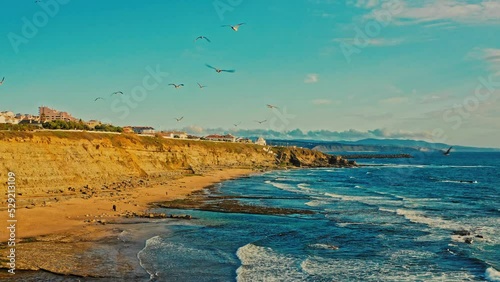 Beautiful  rocky ocean  shore with flying birds during sunset. Drone is hovering along the beautiful  ocean coast with small European city on it.   Beautiful natural landscape with ocean rocky shore. photo