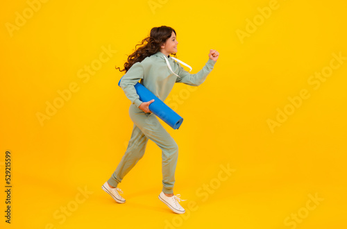 Run and jump. Teenage girl dressed in sports uniform, posing in the studio. Child in a posh stylish sports suit in a hoodie with a hood. Advertising sportswear and yoga wear. Healthy kids lifestyle.