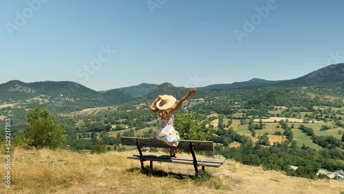 woman sitting on bench admiring countryside france landscape photo