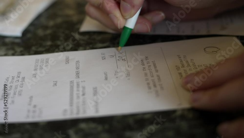 This close up video shows a hand signing a dinner check.