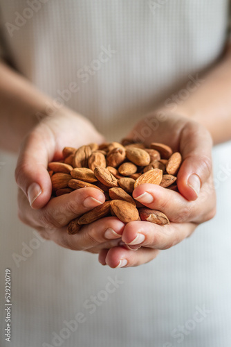 Woman holding almond nuts in hands on fresh background photo