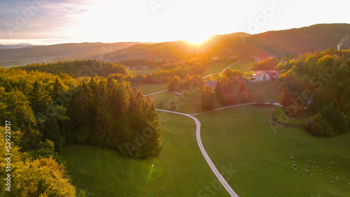 AERIAL: Idyllic hilly countryside and villages bathing in rays of autumn sunset photo