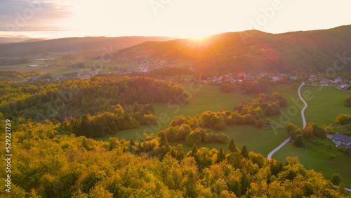 AERIAL: Picturesque hilly countryside with villages and farmland in golden light photo
