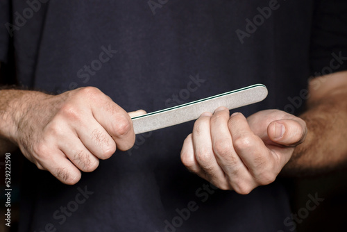 A man holds a nail file in his hands and saws his nails photo