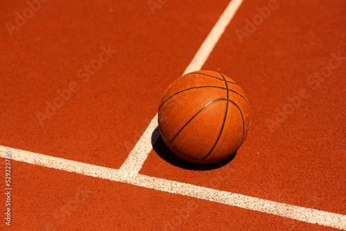 Top view orange ball for basketball lying on the rubber sport court. Sport red ground outdoor in the yard