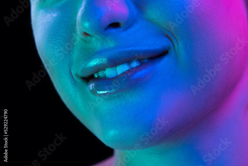 Closeup female lips, cheeks and nose isolated over dark background in neon light. Concept of cosmetology, skincare, cosmetics, plastic surgery, ad