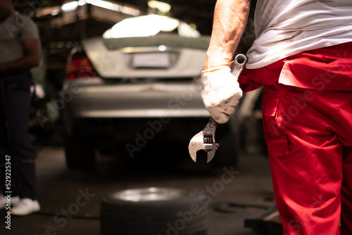 male mechanic holding wrench at auto garage. repair and maintenance career. after service, mechanic holding wrench.