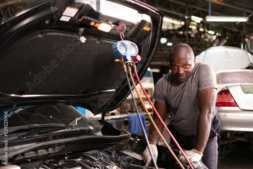 African american mechanics - man examining car engine. Auto mechanic working in garage.Car Mechanic Detailed Vehicle Inspection. Auto Service Center Theme.