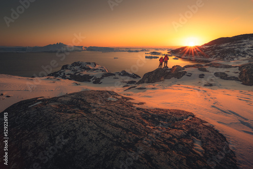 Photographers taking picture of sunset in greenland during winter next to ilulissat icefiord