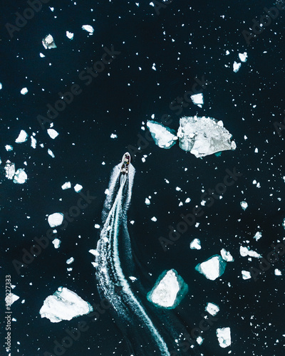 Aerial view of the boat on the sea between small icebergs