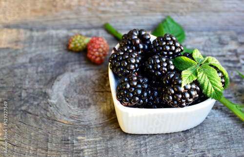 Freshly picked organic blackberries in a white heart shaped bowl on a dark background.Blackberry.Healthy eating,vegan food or diet concept.Selective focus.