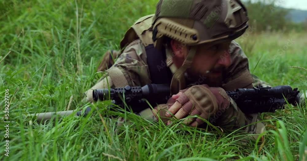 the soldier, having crossed his weapon in his hands, crawls on the grass, hiding from enemy fire. Ukrainian soldier. NATO. war the soldier, having crossed his weapon in his hands, crawls on the grass, hiding from enemy fire. Ukrainian soldier. NATO. war