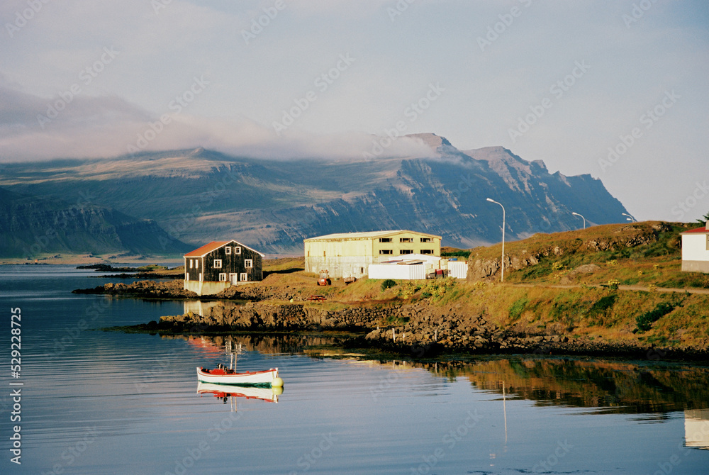 Obraz premium Houses and a boat on the lake with mountain views in Iceland. Grainy film in the style of old photos. High quality photo
