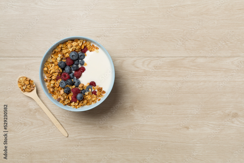 Bowl with granola, yogurt and fresh berries on wooden background, top view Bowl with granola, yogurt and fresh berries on wooden background, top view