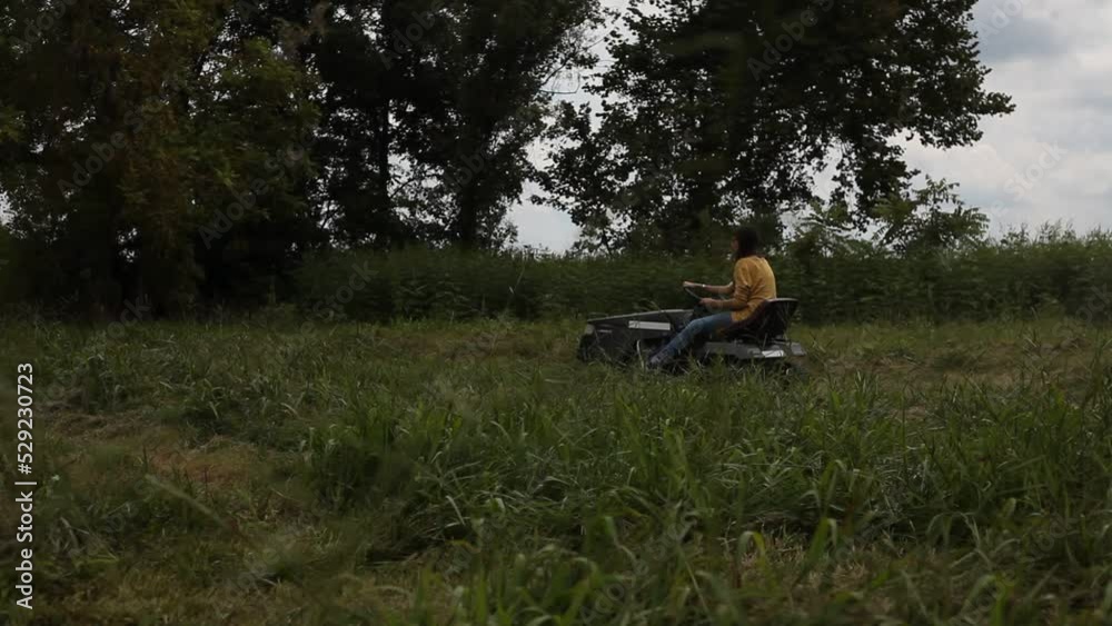 Young Female Farmer Cuts Grass on Riding Tractor Mower Young Female Farmer Cuts Grass on Riding Tractor Mower