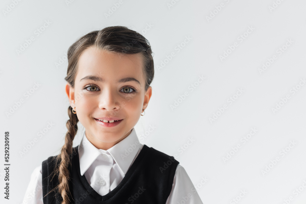 portrait of happy schoolgirl in white shirt and vest looking at camera isolated on grey. portrait of happy schoolgirl in white shirt and vest looking at camera isolated on grey.