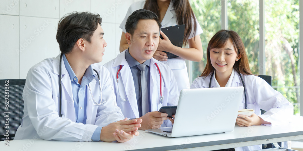 Young asian intern, young male and female doctor sitting with Senior Doctor talk and discuss using laptop in office. Young asian intern, young male and female doctor sitting with Senior Doctor talk and discuss using laptop in office.
