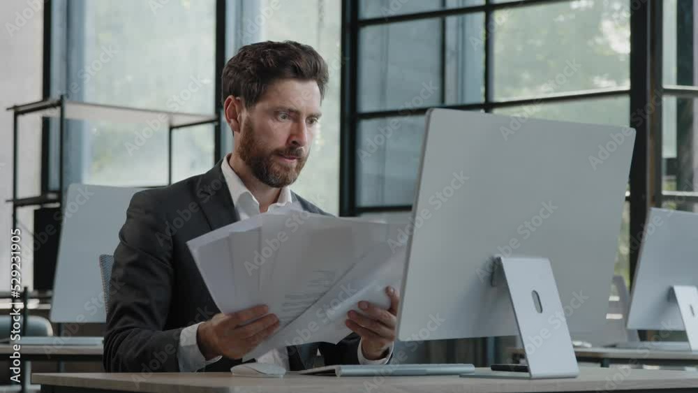 Unmotivated tired exhausted burnout adult worker manager businessman sitting in office with paperwork difficult task incorrect data in papers and computer error throws documents holding head with sad