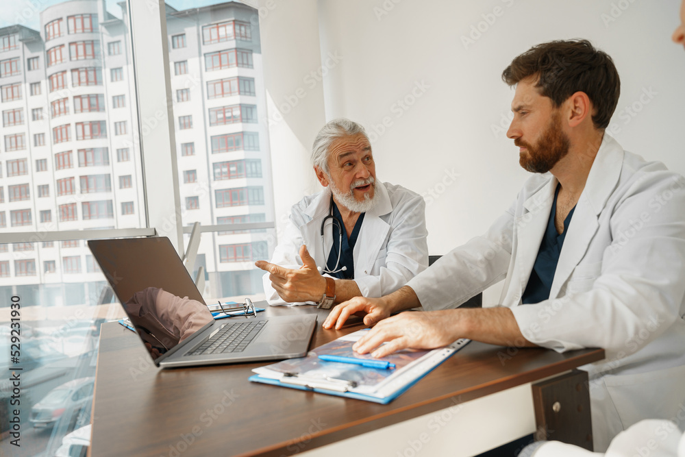 Group of doctors sitting at meeting table in conference room during seminar. High quality photo