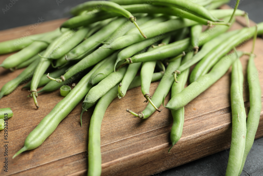 Obraz premium Fresh green beans on wooden board, closeup