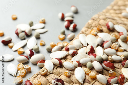 Mixed vegetable seeds and wicker mat on grey background, closeup